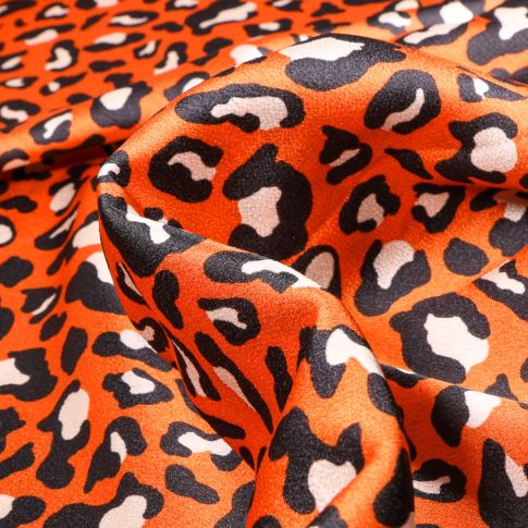 Tissu Satin Tâches léopard blanches et noires sur fond Orange