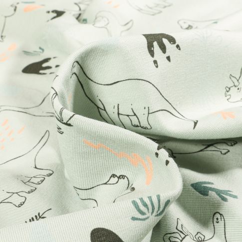 Tissu Jersey Coton Dinosaures et feuillages sur fond Vert amande