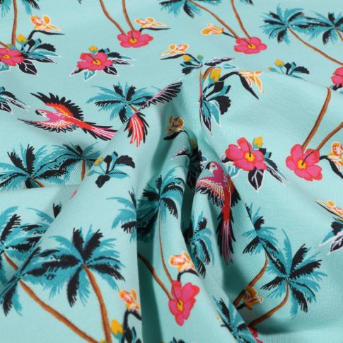 Tissu Jersey Coton Palmiers fleurs d'hibiscus et perroquet sur fond Bleu lagon