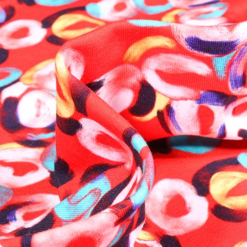 Tissu Jersey Coton Formes abstraites multicolores sur fond Rouge